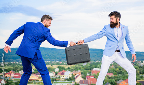 Fraud and extortion concept. Rascal racketeer extortionist cheating handover. Men suits handover briefcase. Business deal landscape background. Businessman takes away briefcase from business partner