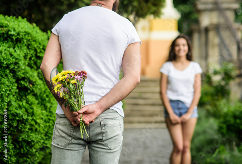 Man hides flower bouquet behind back while waits girl romantic date. First impression always important. Surprise for her. Couple meeting for date park background. Guy prepared surprise for girlfriend