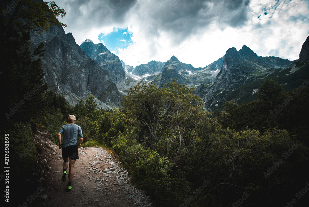 Trail runner run in mountains, sport photo in nature