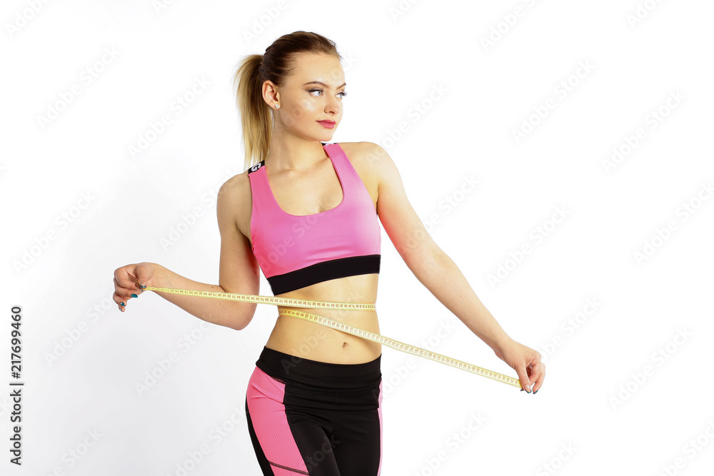 A sporty young girl measures a waist with a centimeter isolated on white background A sporty young girl measures a waist with a centimeter isolated on white background