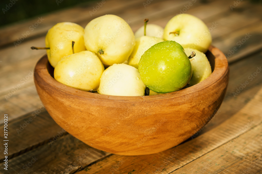 delicious green apples in a bowl on an old wooden table in the summer