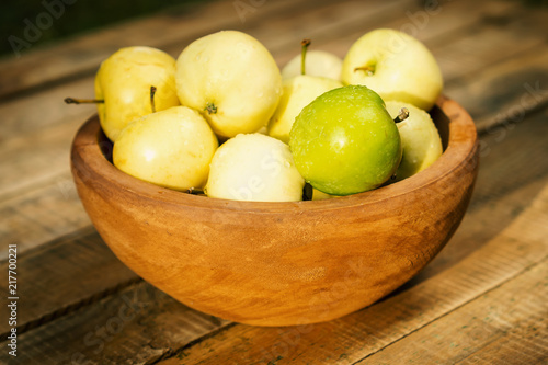 delicious green apples in a bowl on an old wooden table in the summer
