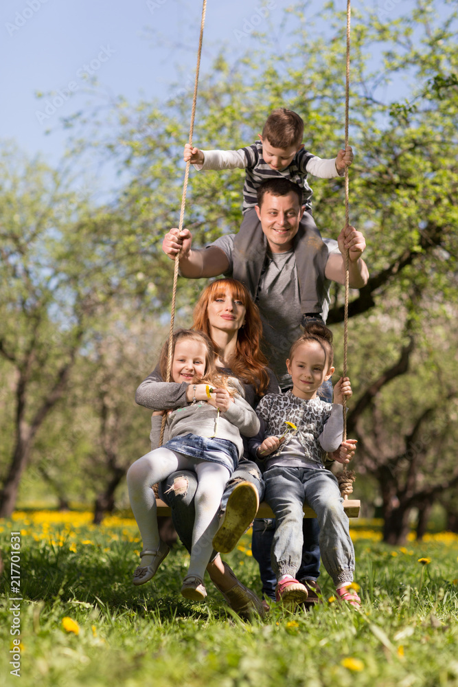 Friendly, cheerful family on a swing in the Park