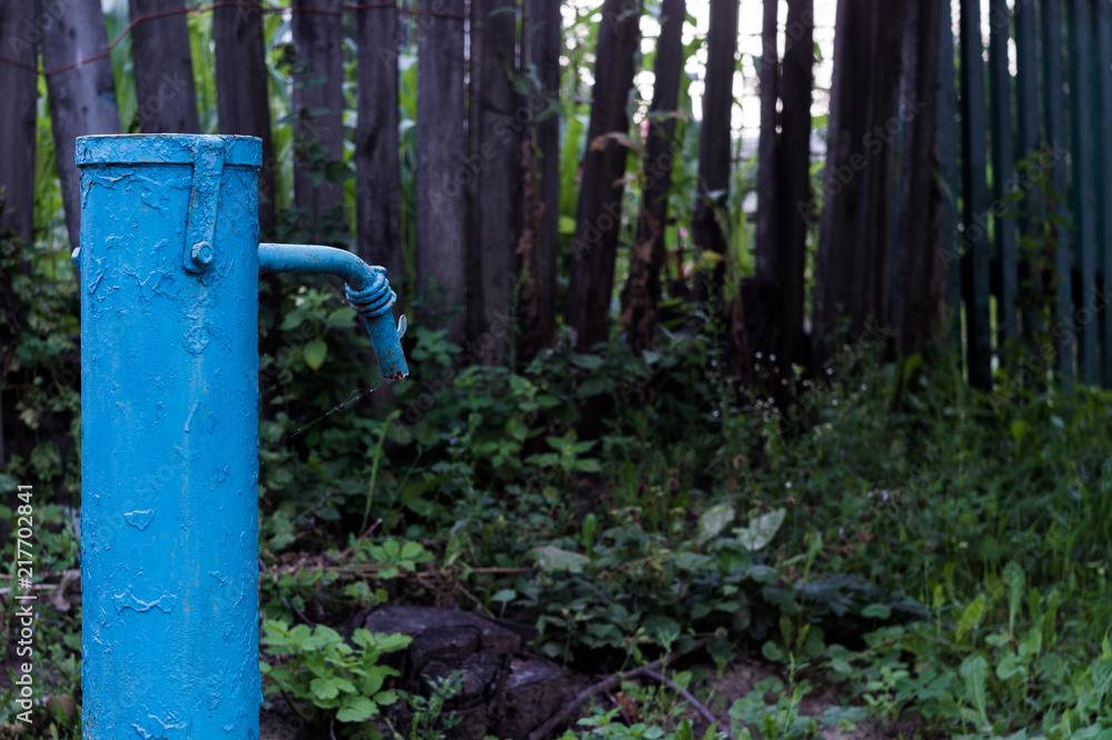 The blue broken water hydrant. Paint is very old and cracked. The blue broken water hydrant. Paint is very old and cracked.