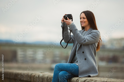 Happy tourist is taking photos outdoor on cloudy day. 