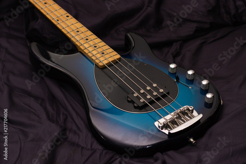 Blue sunburst bass guitar on black fabric background