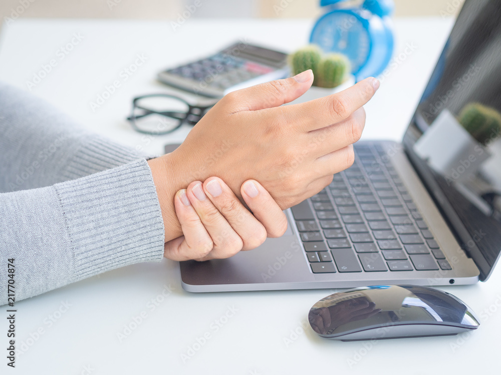 Closeup woman holding her wrist pain from using computer long time