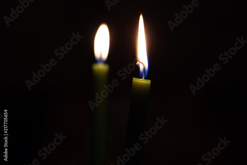 Two green candles flame burning on black background 