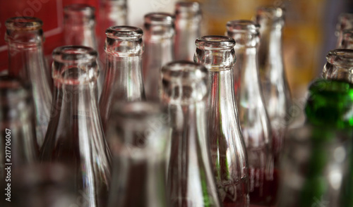Many used glass bottles arranged in rows for recycling. Opened empty soda bottles background