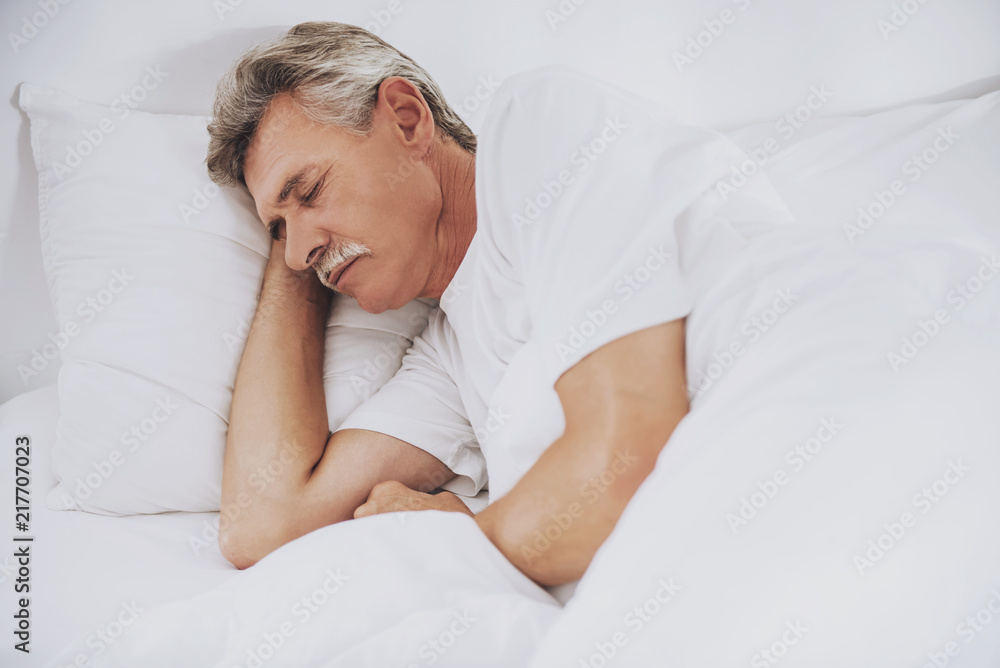 Old Man Sleeping in Comfortable White Bed at Home. Old Man Sleeping in Comfortable White Bed at Home.