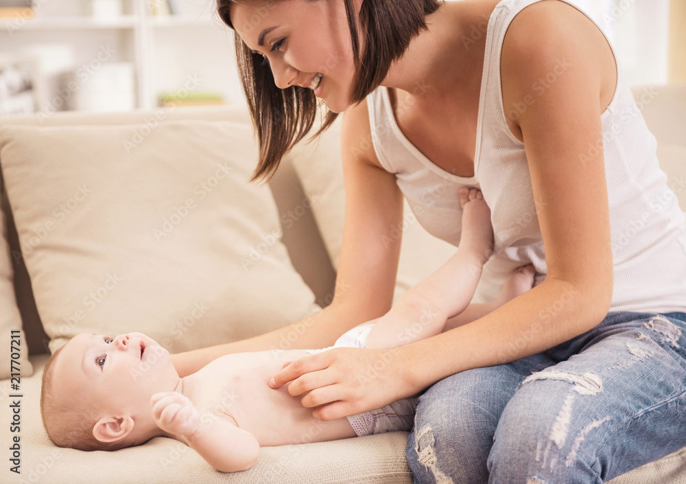 Cute Baby Lying on Sofa with Mother Sitting near.