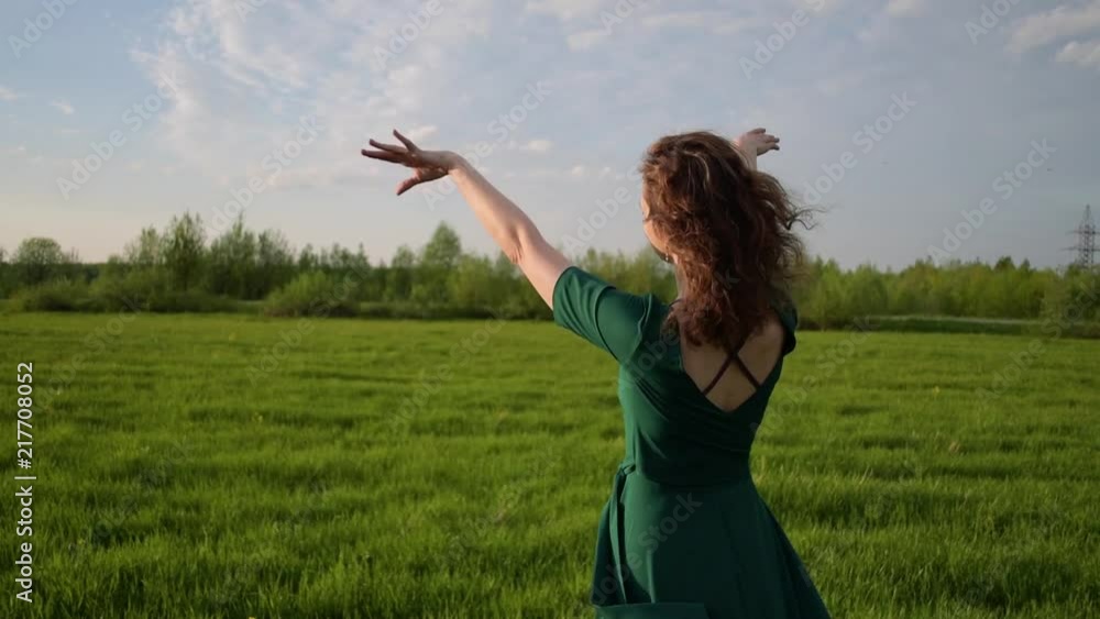 Young beautiful woman in a beautiful dress walking around the field at sunset