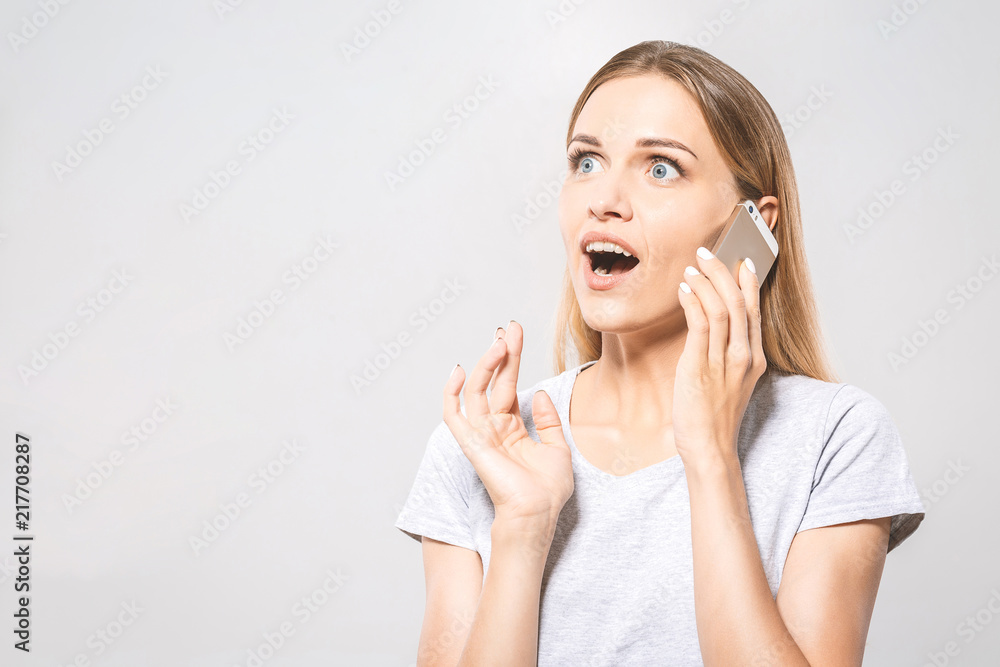 Wow! It's amazing! Photo of surprised cheerful cute beautiful young woman chatting by mobile phone isolated over white wall background. Wow! It's amazing! Photo of surprised cheerful cute beautiful young woman chatting by mobile phone isolated over white wall background.