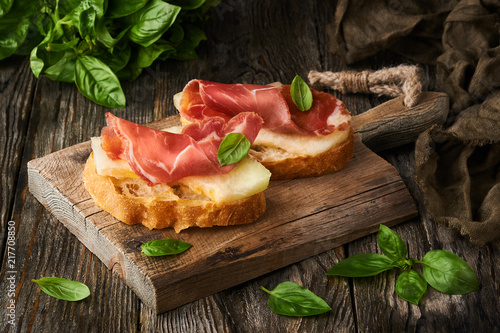 photo of tasty bread slices with bacon and melon