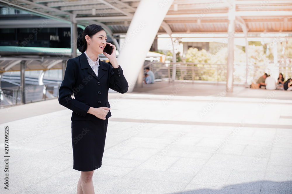 Asian business woman smile and hold cell phone to talk about business success, and copy space for text Asian business woman smile and hold cell phone to talk about business success, and copy space for text