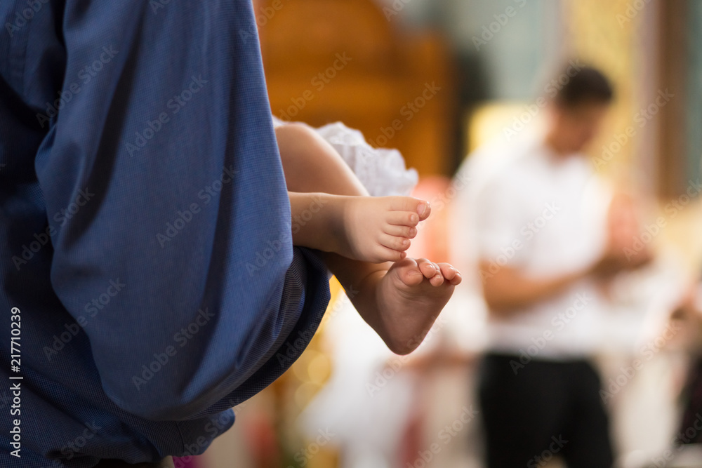 baby legs on the hands of godparents in the cathedral