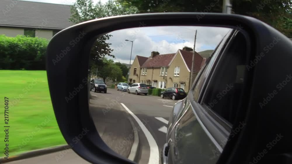Reflection in a car wing mirror of a drive along a village road. Reflection in a car wing mirror of a drive along a village road.
