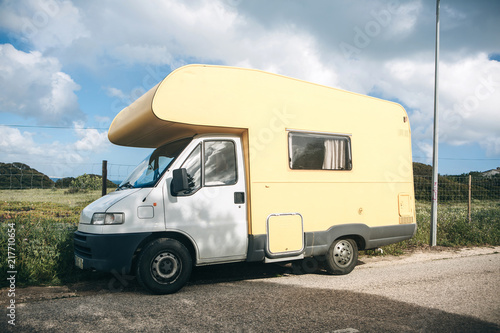 A motor home or a house on wheels is parked on the side of the road. Road trip or traveling by car. People sleep inside to rest for further travel.