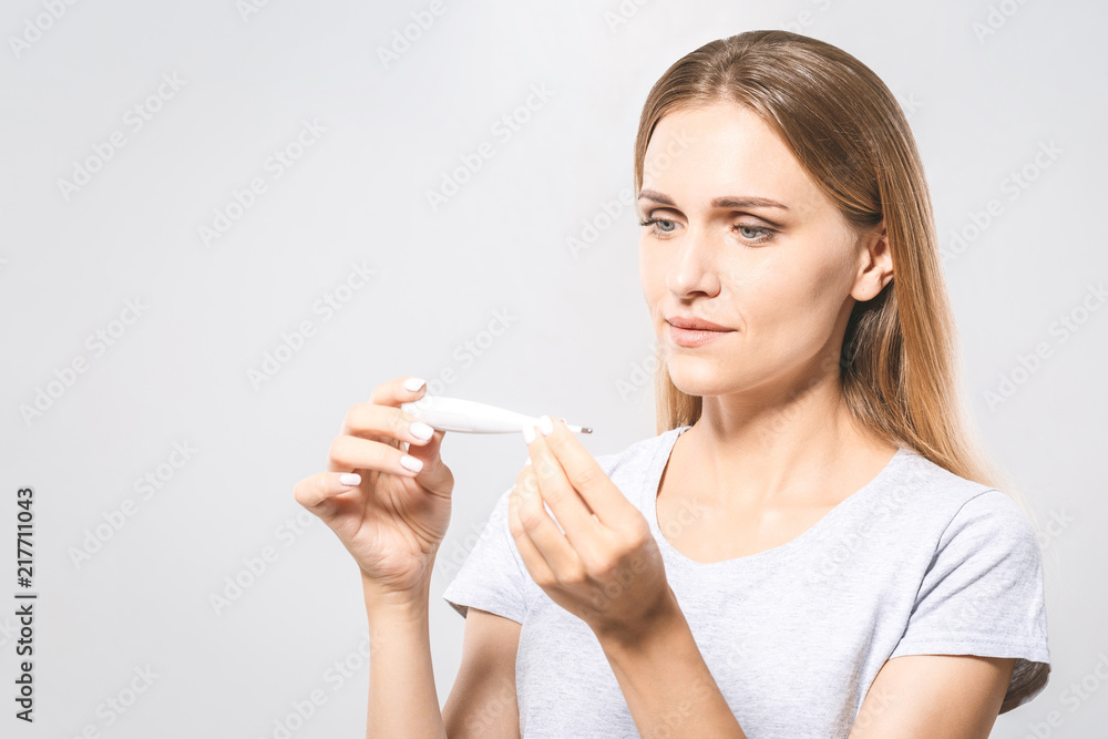 Portrait of a worried young beautiful woman checking her temperature. White background, flu. Portrait of a worried young beautiful woman checking her temperature. White background, flu.