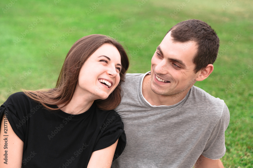 Beautiful couple sit on a blanket on the grass