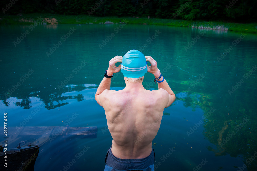 Swimming in nature, man preparing for swim in blue lake