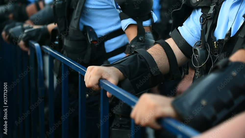 Police officer hands on a security fence during a riot Police officer hands on a security fence during a riot