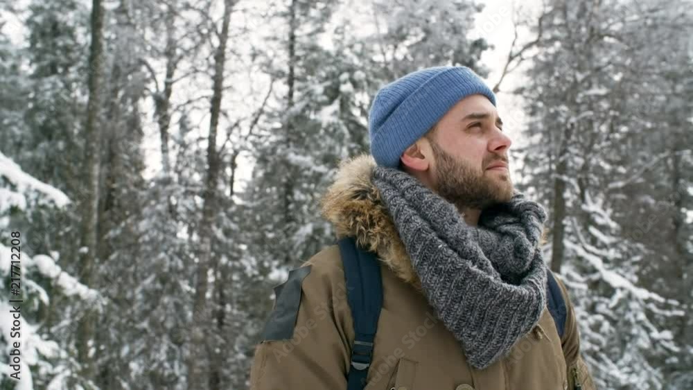 Happy young man looking around at beautiful winter nature in national park and then looking at camera and happily smiling Happy young man looking around at beautiful winter nature in national park and then looking at camera and happily smiling