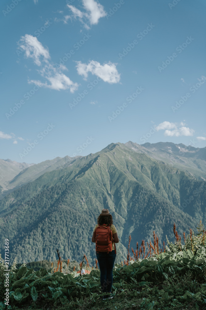 Woman traveler hipster with backpack looking forward at amazing mountains and valley view