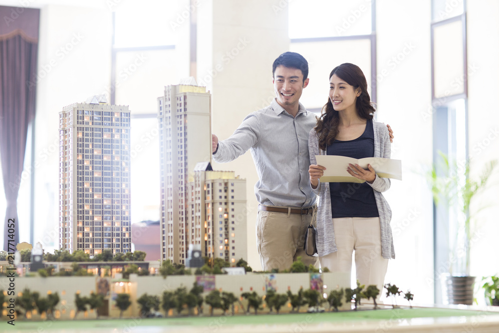 Happy young couple buying new house from sales center Happy young couple buying new house from sales center