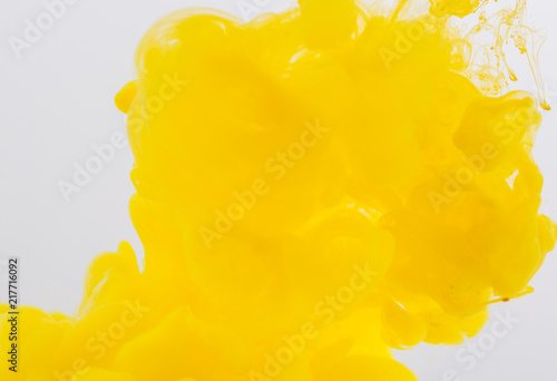 Abstract paint background. Yellow acrylic paint in water.