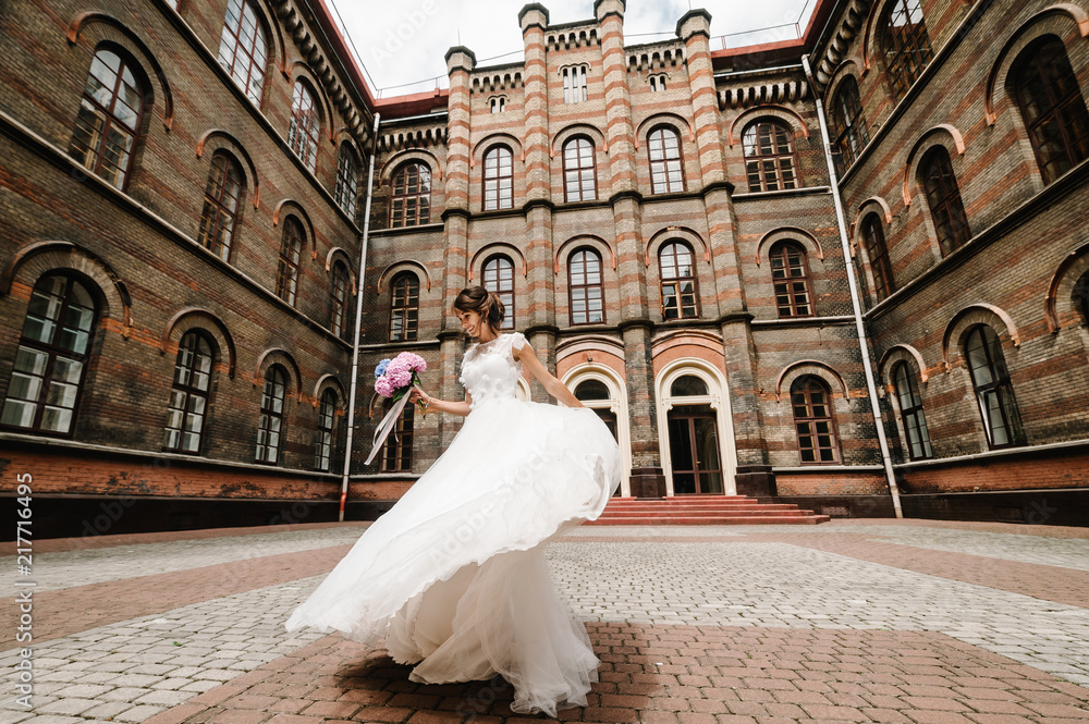 Obraz premium Beautiful portrait bride are dancing and spinning back near ancient restored architecture, old building, old house outside, vintage palace outdoor.