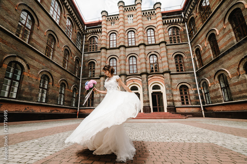 Beautiful portrait bride are dancing and spinning back near ancient restored architecture, old building, old house outside, vintage palace outdoor. © Serhii
