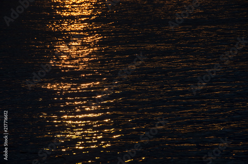 dark water during dusk with glare on the surface from the sun