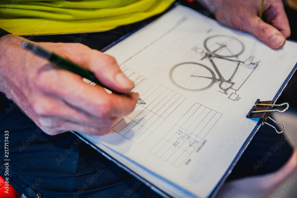 Obraz premium Bicycle setting - man in bicycle service write parameters of bike, on catalog