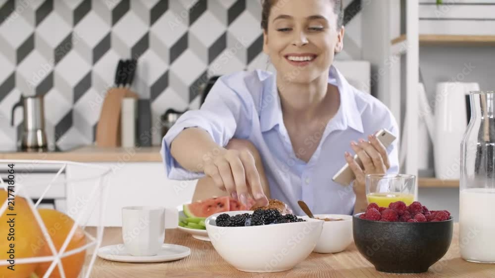 Young woman using a mobile phone during breakfast in kitchen Young woman using a mobile phone during breakfast in kitchen