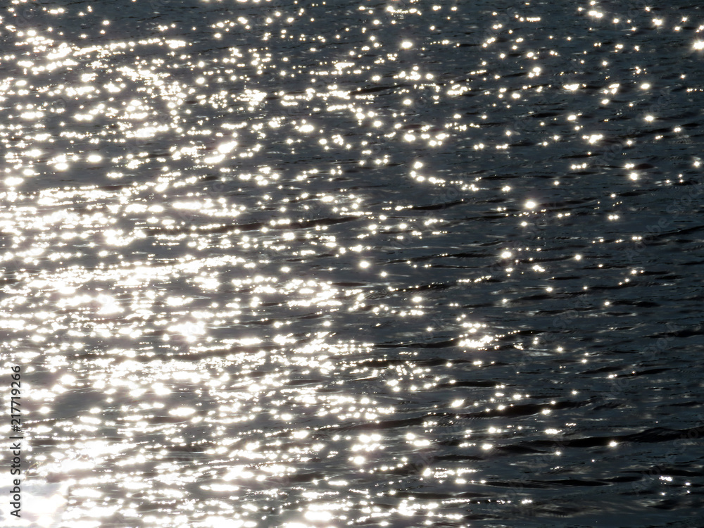 Black water texture background with ripples. Shimmering waves on water surface