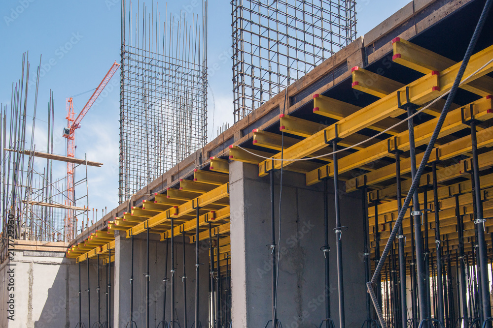 reinforced concrete structures of the building under construction. scaffolding and support. construction crane Photos | Adobe Stock