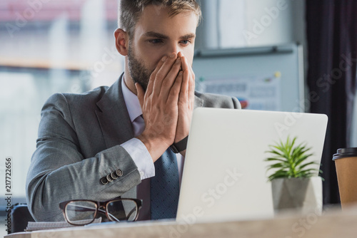 shocked young businessman using laptop in office