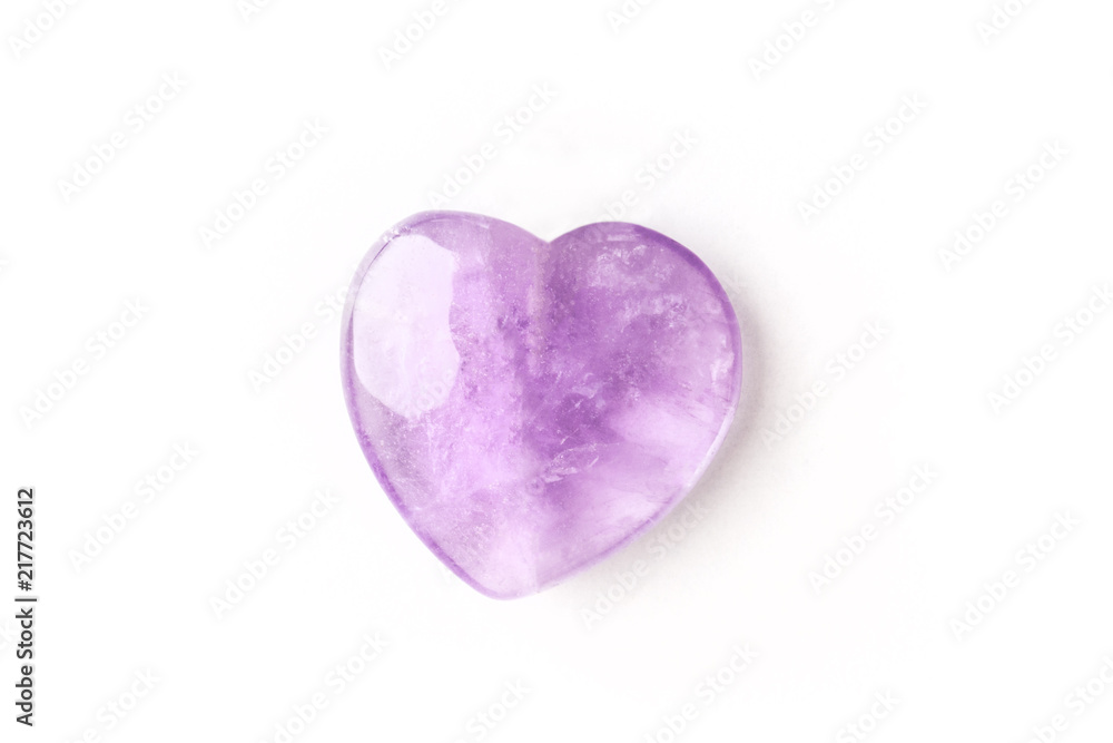 Overhead photo of a purple amethyst crystal heart on a white background with copy space