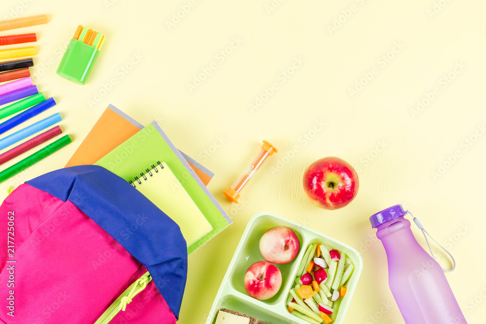 School concept flat lay. Kid backpack, lunchbox, water bottle, notebook, markers on wooden desktop School concept flat lay. Kid backpack, lunchbox, water bottle, notebook, markers on wooden desktop
