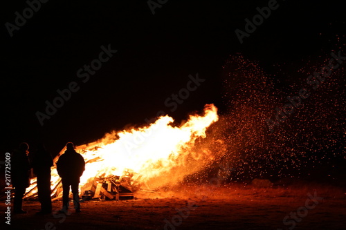 Fototapeta Naklejka Na Ścianę i Meble -  People standing around large bonfire in wind