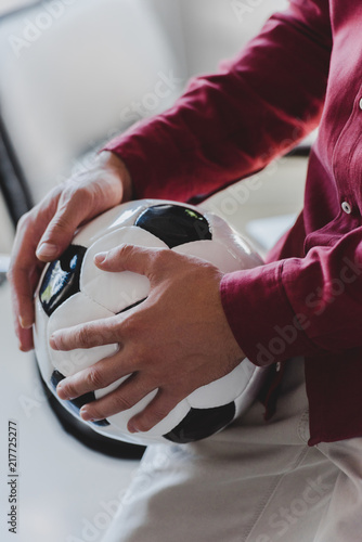cropped shot of businessman holding soccer ball in office