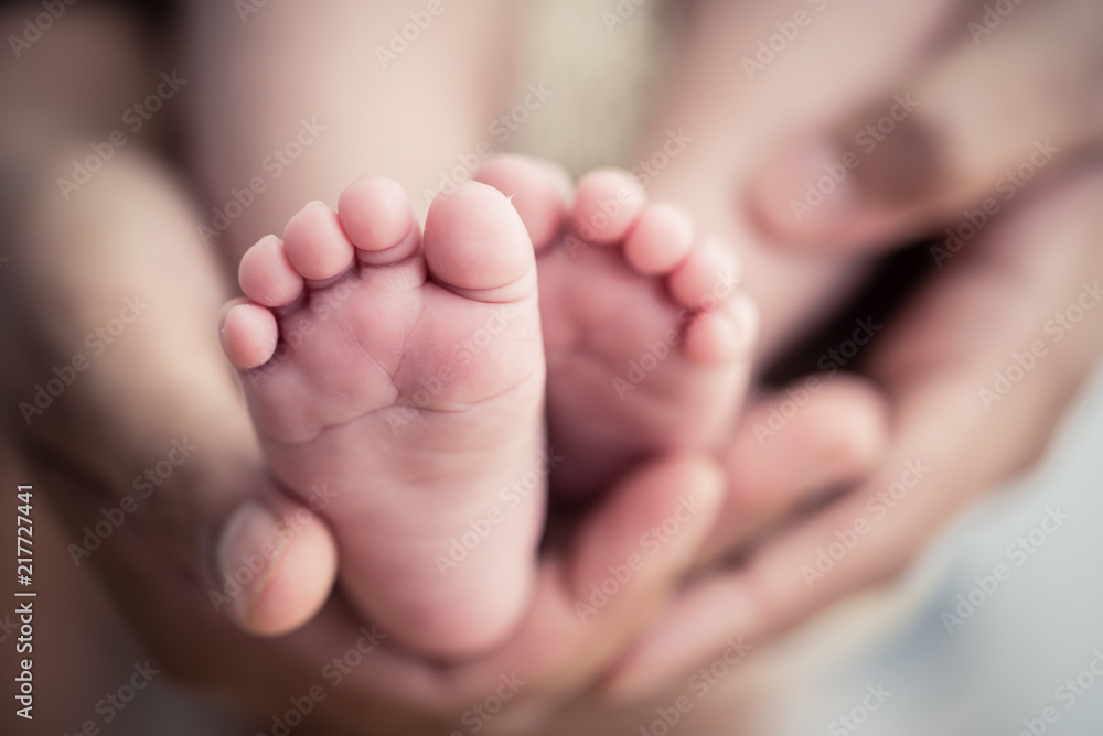 Feet of a newborn baby in the hands of parents. Happy Family oncept. Mum and Dad hug their baby's legs. Feet of a newborn baby in the hands of parents. Happy Family oncept. Mum and Dad hug their baby's legs.