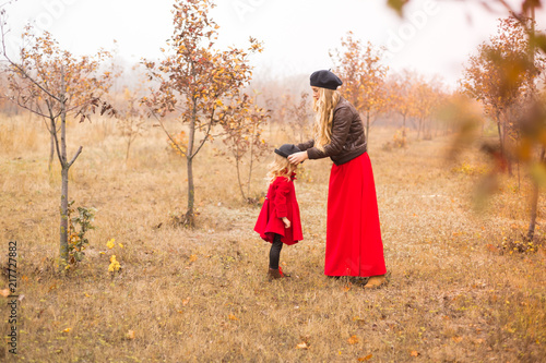 young mother plays with her little daughter in the autumn garden