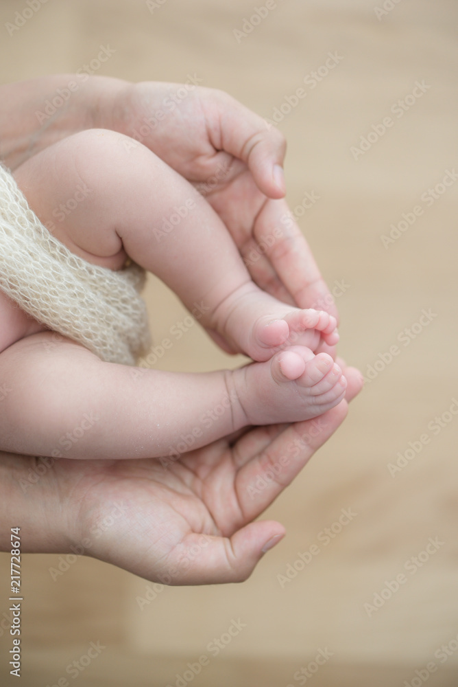 Feet of a newborn baby in the hands of parents. Happy Family oncept. Mum and Dad hug their baby's legs. Feet of a newborn baby in the hands of parents. Happy Family oncept. Mum and Dad hug their baby's legs.