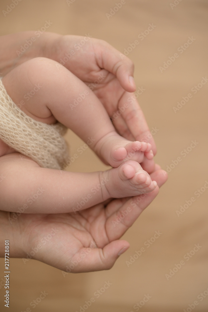 Feet of a newborn baby in the hands of parents. Happy Family oncept. Mum and Dad hug their baby's legs.