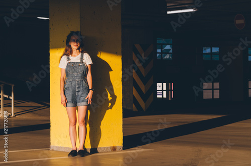 Smiling Girl in a jeans overalls standing in the parking photo