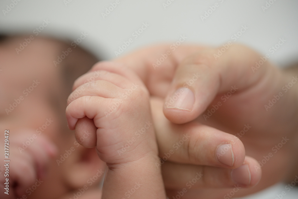 Newborn baby holding finger of mother / father. Happy Family and Baby protection concept. Mom and dad holding the hand of their child. Newborn baby holding finger of mother / father. Happy Family and Baby protection concept. Mom and dad holding the hand of their child.