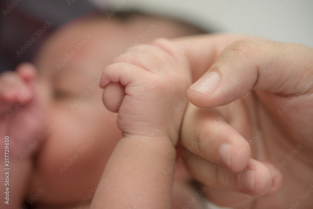 Newborn baby holding finger of mother / father. Happy Family and Baby protection concept. Mom and dad holding the hand of their child. Newborn baby holding finger of mother / father. Happy Family and Baby protection concept. Mom and dad holding the hand of their child.