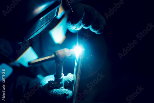 Argon-arc welding welder at the workplace welds the part